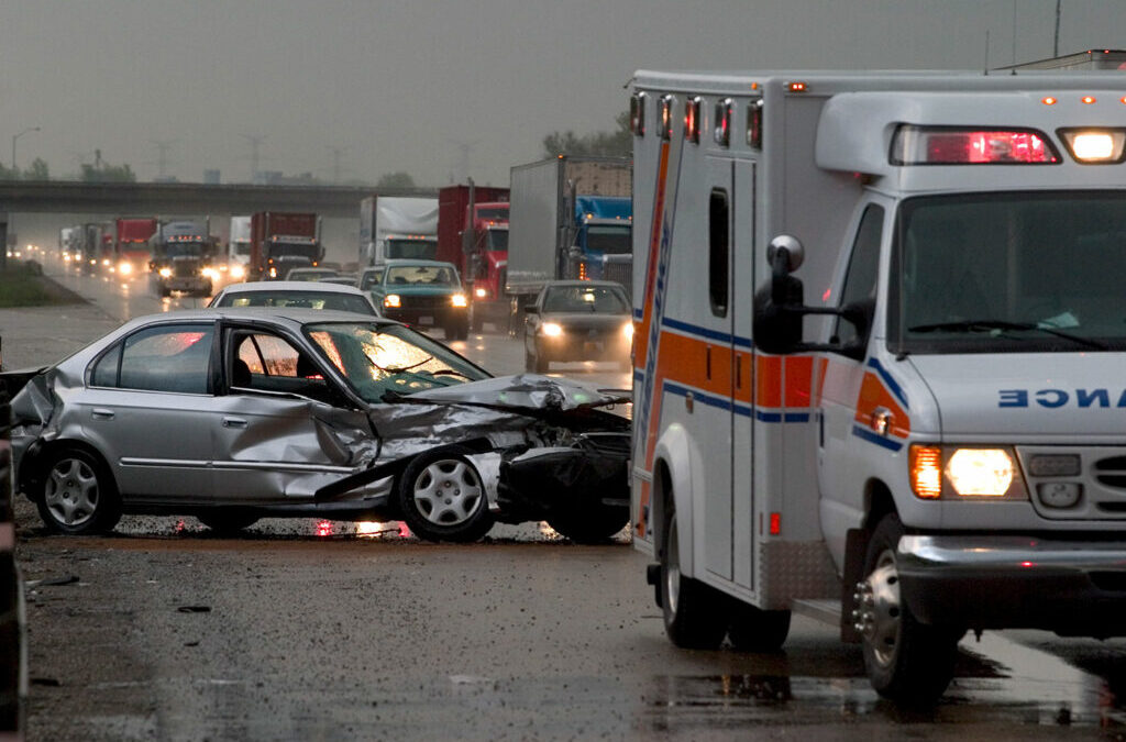 A car accident scene with a damaged vehicle and an ambulance